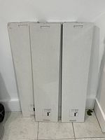 Three boxed IKEA TRANHULT shelves leaning against wall
