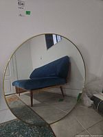 Front view of round mirror with gold frame leaning against wall