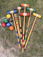 Full set laid on grass showing six mallets, six balls, white metal wickets