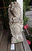 Front view of concrete lion statue on wooden deck