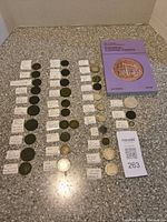 Overall lot showing all coins laid out with handwritten tags and reference book