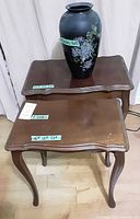 Two wooden end tables stacked with black floral vase on top
