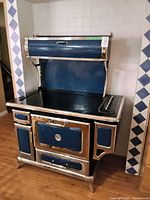 Full view of blue range with hood, cooktop and chrome trim