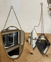 Large gold-tone shield mirror and copper double-diamond mirror hanging on wall
