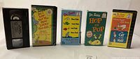 Front view of five VHS items showing titles and cases