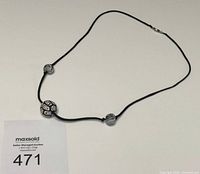 Full view of necklace laid flat showing cord, beads, clasp