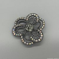 Front view of gunmetal filigree flower brooch showing rhinestone placement