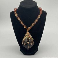 Full view of amber glass bead necklace on display bust