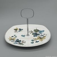 Full view of porcelain cake stand showing floral design and chrome handle