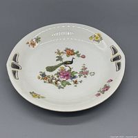 Top view of porcelain serving plate showing peacock floral motif and gold trim