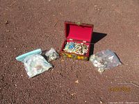 decorative box open with contents, two sealed bead bags alongside