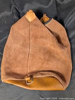 Front view of brown suede backpack showing overall shape and leather bottom with metal D-ring