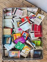 Tin containing many assorted Vancouver-branded matchbooks