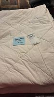 Folded white quilted duvet with lot tag visible