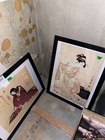 Pair of framed geisha prints leaning against wall
