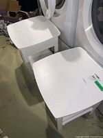 Two white end tables beside laundry machines