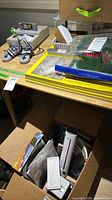 Top and legs of light wood table partially covered by assorted items