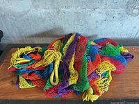 Multicolor net hammock coiled on tabletop showing woven mesh and braided loop ends