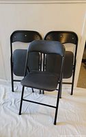 Three black folding chairs opened for display