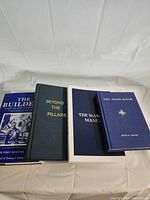 Four Masonic books laid out showing covers
