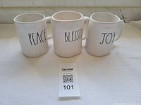 Front view of three mugs showing PEACE, BLESSED, JOY text