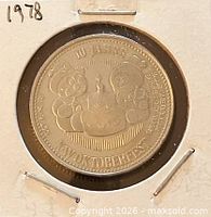 Obverse side in holder, shows cake and mascots design with inscriptions