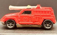 Left side view of red Hot Wheels fire truck showing roof cannon and wheel detail