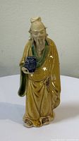Front view of glazed pottery scholar holding wine vat