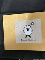 Gold gift box lid with sheep illustration and Dream Journal text