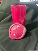 Pink insulated tumbler standing with wrapped lid in front