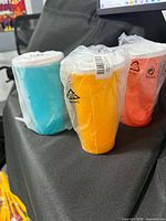Three sealed tumblers in aqua, yellow and coral