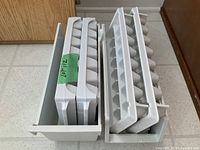 Two freezer bins filled with stacked ice cube trays