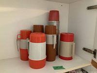 Group of six thermoses on shelf
