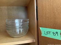 Stack of five clear glass bowls on shelf