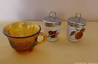 Amber carnival glass cup and two porcelain egg coddlers with chrome lids