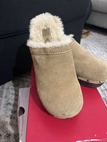 Front view of tan suede clog with faux fur collar on red box