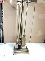 Full view of brass fireplace tool set on stand