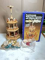 Assembled wooden Christmas pyramid beside original box with loose parts bags