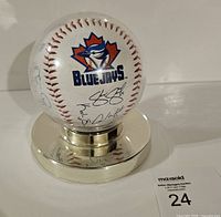 Front view of baseball showing Blue Jays logo and signatures on chrome stand