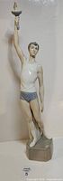 Full view of figurine front with torch raised
