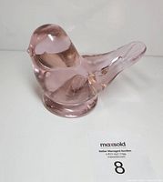 Front angled view of pink glass bird figurine with base