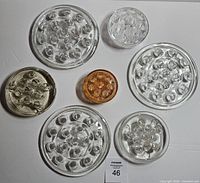 Seven vintage glass flower frogs laid out on white background