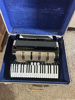 Accordion in open blue-lined case showing piano keyboard and grille