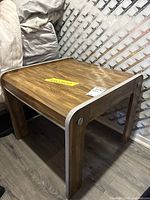 Square wood veneer side table with silver trim shown from front/side