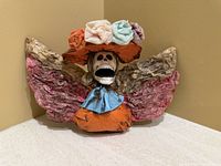 Front view of papier-mâché Catrina bust with hat, flowers and wings