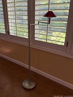 Full view of metal swing-arm floor lamp standing by window