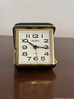 Front view of Seth Thomas travel alarm clock open showing dial and hands