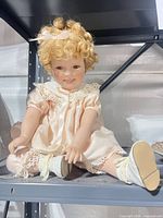 Full view of seated porcelain doll on shelf