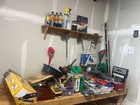 Workbench with tile cutter box, oil bottles, clamps, level, work light, assorted hand tools
