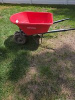 Side view of red Craftsman wheelbarrow on grass